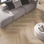 lichte beige eiken vloer met visgraatpatroon en fijne houtstructuur in moderne woonkamer met grijs bankstel en witte ronde salontafel