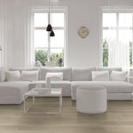 lichte vloer met brede planken in licht beige eiken houtlook, modern interieur met groot wit stoffen hoekbank en transparante salontafel