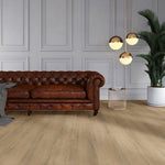licht beige eiken vloer met brede planken en subtiele houtstructuur in een moderne woonkamer met een donkerbruin leren chesterfield bank en gouden hanglampen