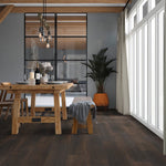 donkerbruin eiken vloer met brede planken en een houtstructuur in een lichte, moderne eetkamer met houten tafel, bankje, grote ramen en metalen scheidingswand