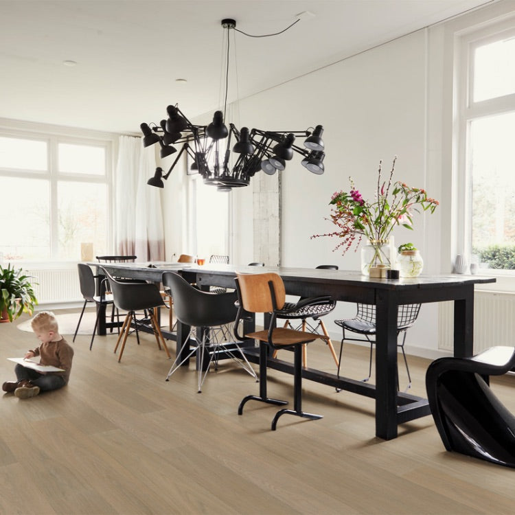 lichte beige eiken vloer met brede planken en subtiele houtnerfstructuur in een lichte woonkamer met zwarte eetkamerstoelen en een lange zwarte eettafel