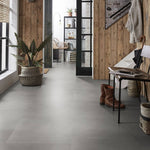 lichte asgrijze tegelvloer met grote plavuizen en een subtiel golvend streeppatroon in een moderne hal met houten wandbekleding
