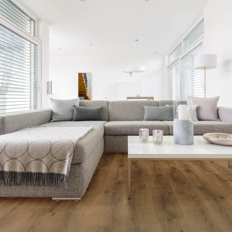 lichte eiken vloer met brede planken en natuurlijke houtstructuur in moderne woonkamer met grijze hoekbank en wit salontafel