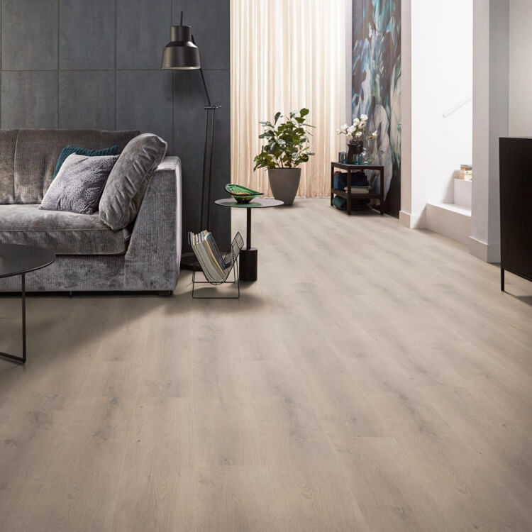 lichte vloer in licht eiken kleur met een subtiele houtnerfstructuur en brede planken, gecombineerd met een grijs fluwelen bank en moderne zwarte staande lamp in een lichte woonkamer