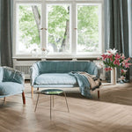 lichte vloer in visgraatpatroon van breed hout met zachte beige eiken kleur, moderne woonkamer met lichtblauwe bank en grote ramen