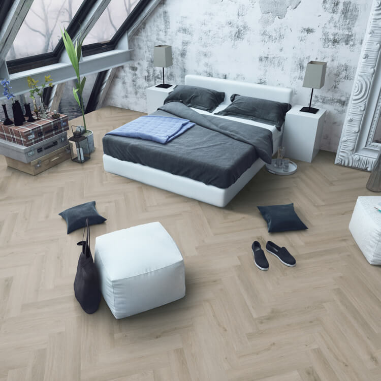 Lichte eiken visgraatvloer met een gladde structuur in een moderne slaapkamer met wit bed en grijs beddengoed.