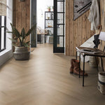 licht eiken vloer met visgraat patroon in brede planken met matte afwerking in moderne hal met houten muurpanelen en donkere metalen deuren
