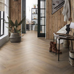 lichte vloer in visgraatpatroon met brede planken in licht beige eiken kleur, gecombineerd met houten wandbekleding in naturelbruine tinten en moderne zwarte metalen deur met glasdelen