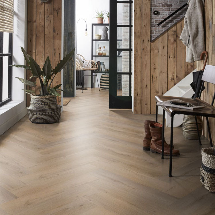 lichte vloer in visgraatpatroon met brede planken in licht beige eiken kleur, gecombineerd met houten wandbekleding in naturelbruine tinten en moderne zwarte metalen deur met glasdelen