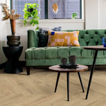 lichte beige eiken visgraatvloer met brede planken, gecombineerd met een groene fluwelen bank en een houten salontafel met zwarte poten