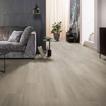 lichte eiken vloer met brede planken in matte afwerking en subtiele houtnerfstructuur in een moderne woonkamer met grijs fluwelen bank en zwarte accessoires