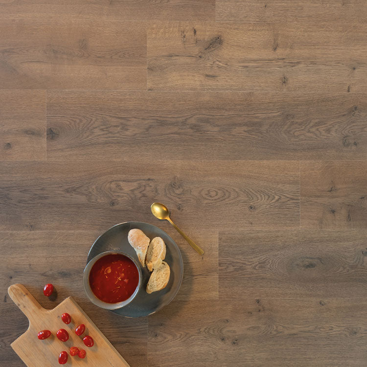 lichte bruin eiken vloer met natuurlijke houtstructuur en brede planken, schotel met tomatensoep en sneetjes brood, houten snijplank met cherrytomaatjes en gouden lepel