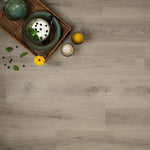 licht grijs eiken vloer met subtiele houtstructuur en brede planken, inclusief dienblad met groen keramisch servies, glaasje sinaasappelsap en kopje koffie met latte art