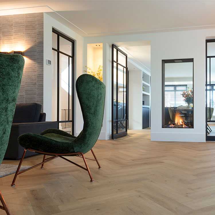 licht eiken visgraatvloer met subtiele houtstructuur en brede planken in moderne woonkamer met groene velvet fauteuils en open haard