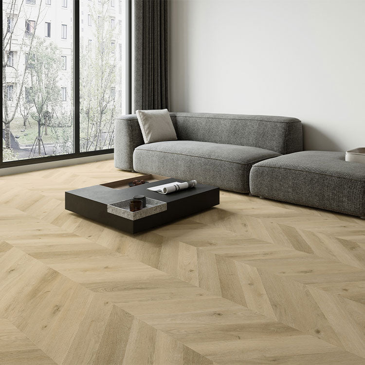 Licht eiken vloer in visgraatmotief met matte structuur, gecombineerd met een donkergrijze moderne hoekbank en grote raampartij in een minimalistisch interieur.