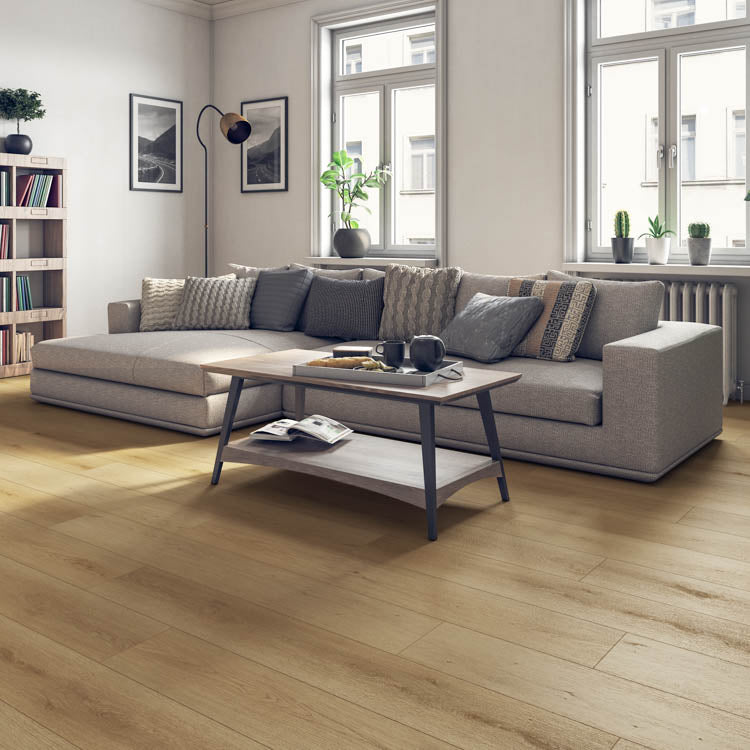 lichte vloer met brede laminaatplanken in licht beige eiken structuur gecombineerd met een modern beige stoffen hoekbank en houten salontafel in een lichte woonkamer met grote ramen