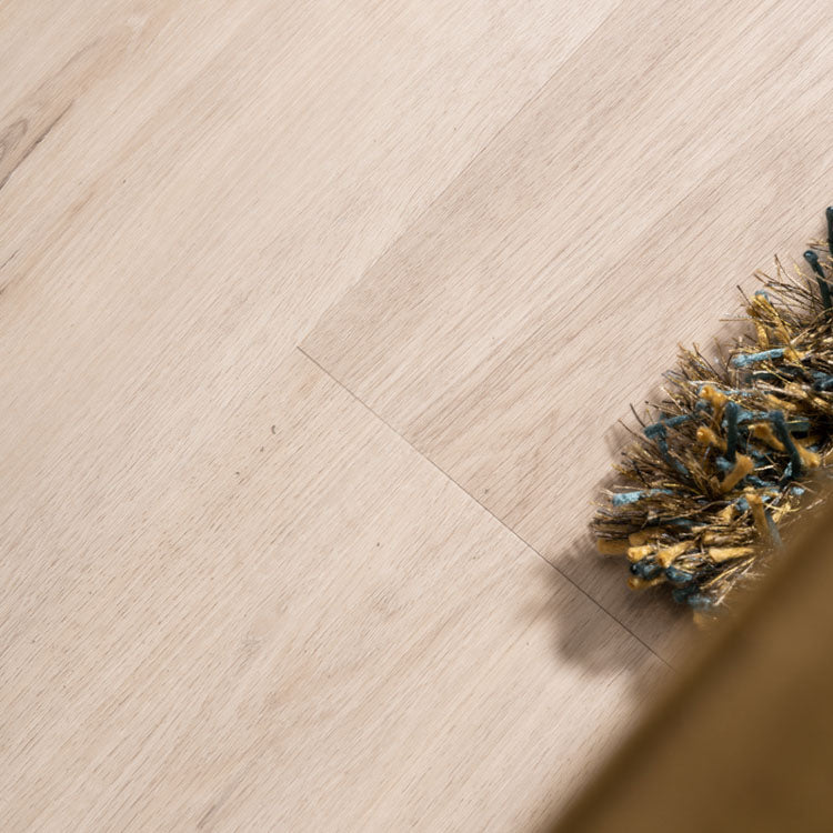 lichte beige eiken vloer met subtiele houtstructuur en brede planken, deels bedekt door een mat met blauwe en gele franjes zichtbaar aan de rechterkant