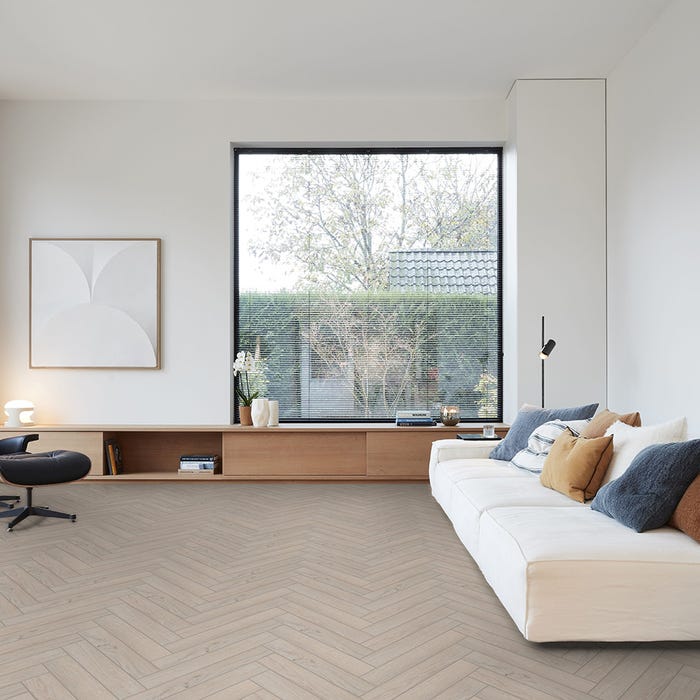 lichte vloer met visgraatpatroon in licht beige eiken kleur, moderne woonkamer met grote raam en witte bank met diverse kussens