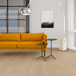 lichte beige eiken vloer met brede planken en subtiele houtstructuur in moderne woonkamer met mosterdgele bank en metalen bijzettafels met houten blad