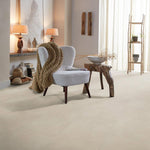lichte beige tegelvloer met grote vierkante tegels en een subtiel effen structuur in een moderne, lichte woonkamer met een lichtgrijze fauteuil en houten bijzettafeltje