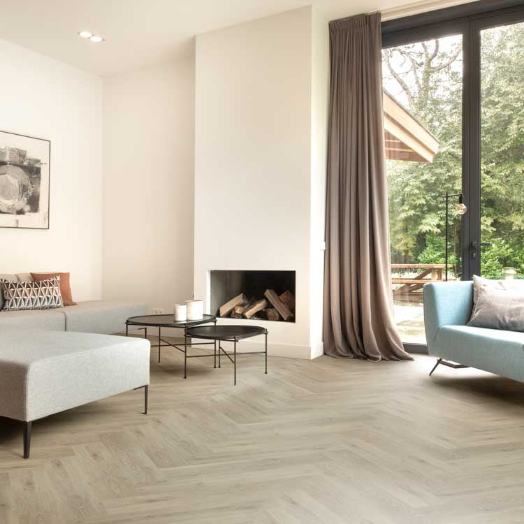 lichte eiken vloer in visgraatpatroon met brede planken in moderne woonkamer met grote ramen en minimalistisch interieur