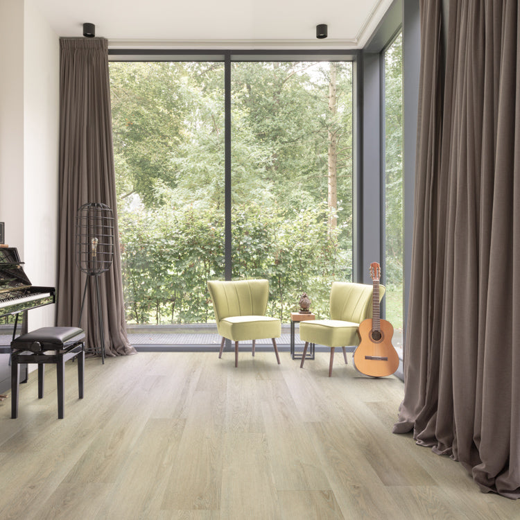 Lichte eiken vloer met brede planken en subtiele houtnerfstructuur in een moderne woonkamer met grote raampartijen, groene fauteuils en donkerbruine gordijnen.