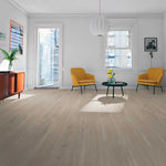 licht beige eiken vloer met brede planken en subtiele houtstructuur in een ruime, lichte woonkamer met twee mosterdgele fauteuils en een zwart rond bijzettafeltje