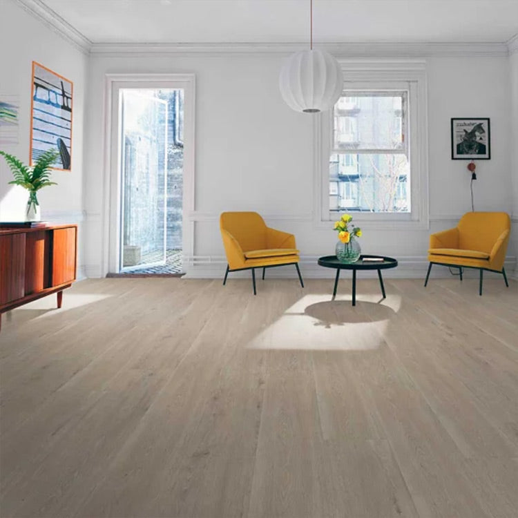 licht beige eiken vloer met brede planken en subtiele houtstructuur in een ruime, lichte woonkamer met twee mosterdgele fauteuils en een zwart rond bijzettafeltje