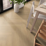 licht eiken vloer in visgraat patroon met een gladde structuur, brede planken, in een lichte woonkamer met houten tafel en witte stoelen