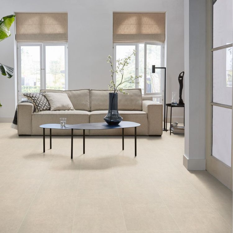 Lichte beige tegelvloer met grote, matte tegels en een subtiel gladde structuur, gecombineerd met een beige stoffen bank en zwarte moderne salontafel in een lichte woonkamer.