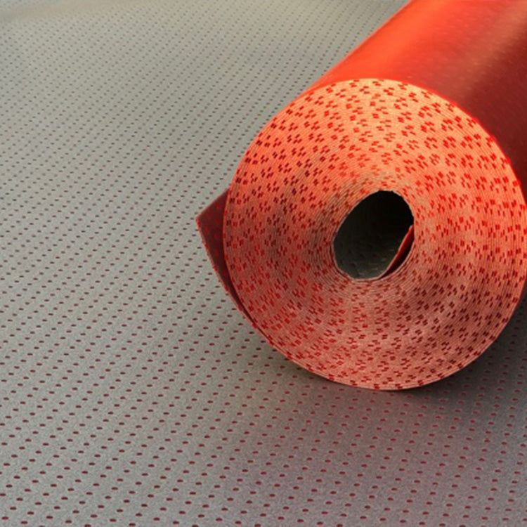 Grijze ondervloer met rood perforatiepatroon, opgerold in een strakke rol met zichtbare structuur van kleine ronde gaatjes.