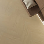 lichte beige eiken vloer met visgraatpatroon, brede planken en natuurlijke houtstructuur, gecombineerd met donkerbruine houten meubelrand en lichtbeige kussen bovenop, moderne strakke afwerking