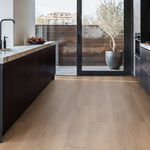 lichte vloer in brede planken met een lichte beige eiken houtstructuur in moderne keuken met donkerbruine kasten en witte marmerlook werkbladen naast glazen schuifpui naar buitenruimte met houten schutting en grote plant in matte grijze pot