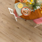 licht eiken vloer met brede planken en natuurlijke houtstructuur onder een houten ronde tafel met servies en grijsgroene tafelloper