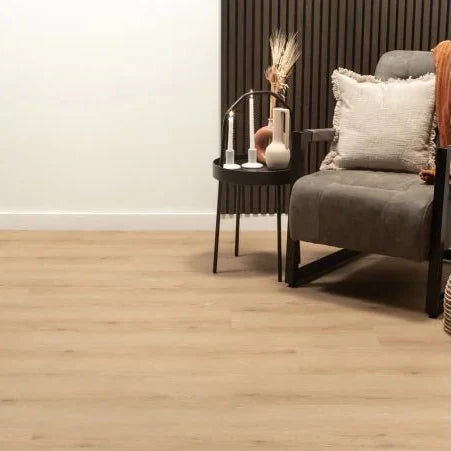 lichte beige eiken vloer met brede planken en een subtiele houtnerfstructuur in een moderne woonkamerhoek met een grijs stoffen fauteuil en een zwart bijzettafeltje met decoratieve vazen en gedroogde takken