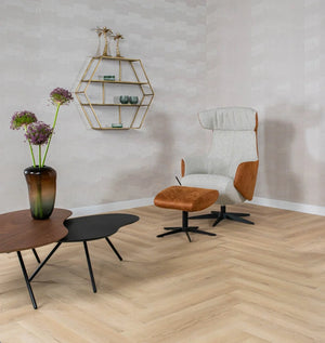 licht eiken visgraatvloer met matte structuur gecombineerd met moderne fauteuil van stof en bruin leer en twee lage tafels, een zwart en een walnootkleurig met metalen poten