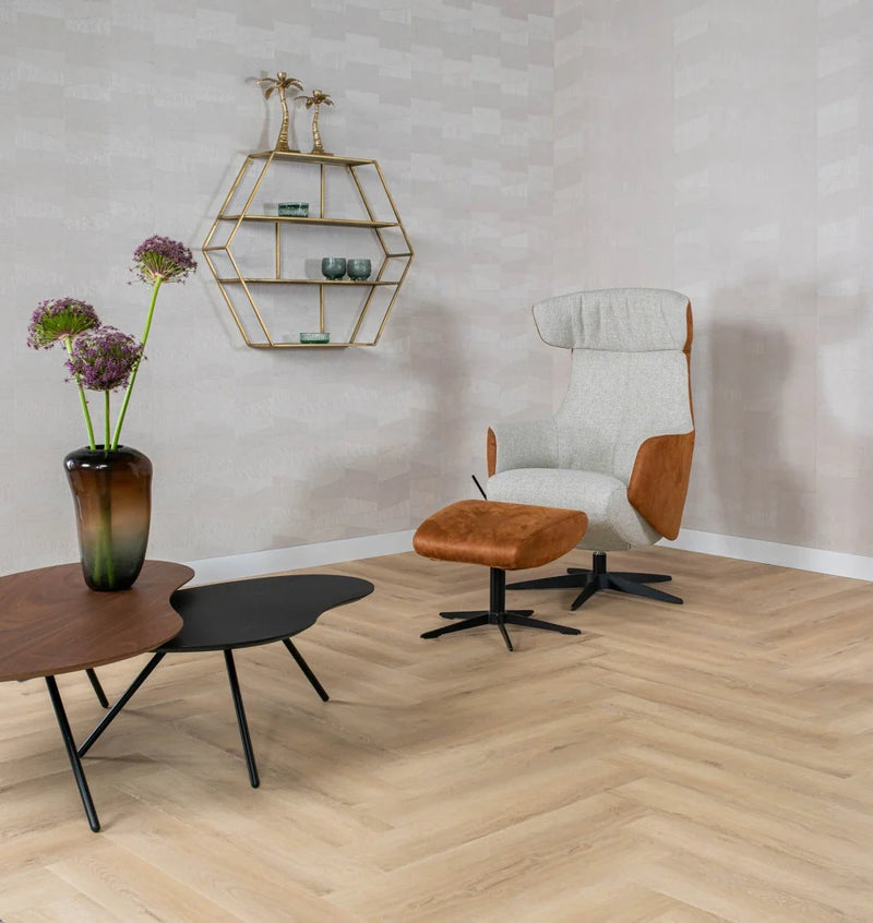 licht eiken visgraatvloer met matte structuur gecombineerd met moderne fauteuil van stof en bruin leer en twee lage tafels, een zwart en een walnootkleurig met metalen poten