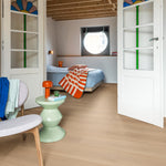 lichte beige eiken vloer met brede planken met subtiele structuur in modern ingerichte slaapkamer met witte binnendeuren met gekleurd glas in lood, lichtgroene bijzettafel en oranje accenten zoals een lampje en deken