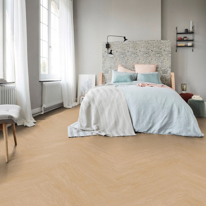 lichte eiken visgraatvloer met fijne houtstructuur in een slaapkamer met lichtgrijze muren en pastelgekleurde accenten in beddengoed en kussenhoesjes