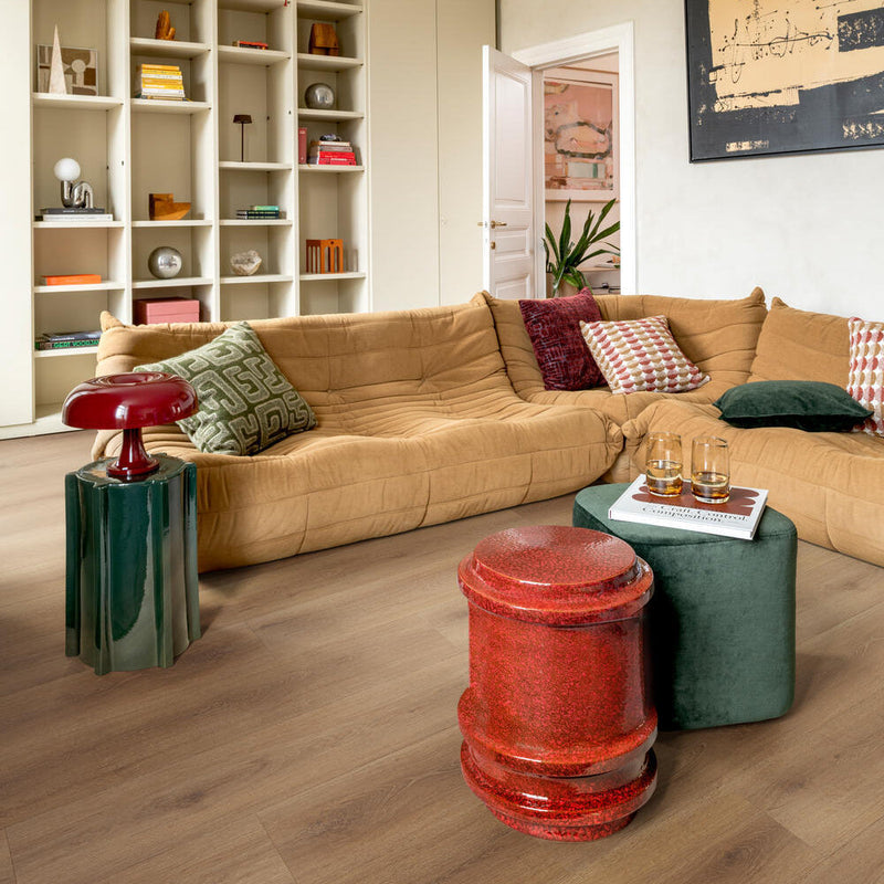 lichte eiken vloer met brede planken en subtiele houtnerfstructuur in moderne woonkamer met beige leren hoekbank en kleurrijke accenten
